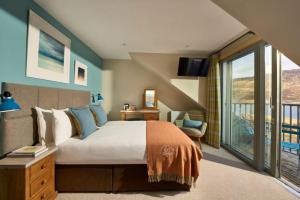 a bedroom with a large bed and a balcony at Kylesku Hotel & Kylesku House, by Highland Coast Hotels in Kylestrome