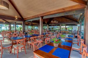an empty restaurant with wooden tables and chairs at Hotel Praia do Sol in Ilhéus