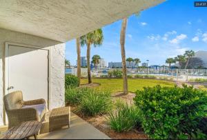 a patio with two chairs and palm trees at Dolphin Point 106C - Harbor Views & Boat Slip in Destin
