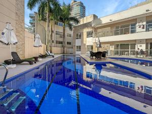 a swimming pool with blue water in a building at 100 metros da praia - Condomínio - 3 suítes - Churrasqueira in Guarujá