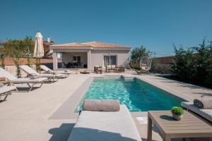 a swimming pool with chairs and a house at Villa Nicoldia with private pool near Laganas in Laganas +55 photos