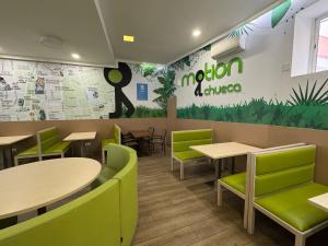马德里Motion Chueca Hostel的有桌子和绿色椅子的餐厅