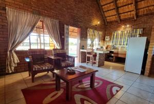 ein Wohnzimmer mit einem Tisch und einer Küche in der Unterkunft Wayside Chalets in Francistown