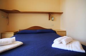 a blue bed with two towels on top of it at Blue Marine Village in Rodi Garganico