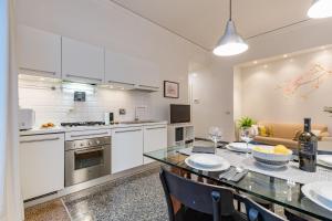 a kitchen with white cabinets and a dining table at Kenzia Suite Aventino in Rome