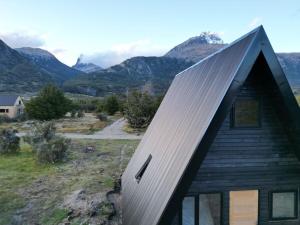 ビージャ・セロ・カスティージョにあるOUTSCAPE l Preciosa Cabaña en Villa Castilloの山を背景に金属屋根を持つ家