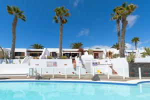 een zwembad met palmbomen op de achtergrond bij Puerto Chico 7 in Playa Blanca