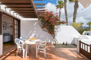 een patio met een witte tafel en stoelen en palmbomen bij Puerto Chico 7 in Playa Blanca