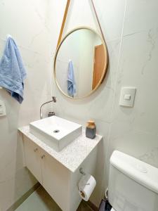 a white bathroom with a sink and a mirror at Apartamento 1 quarto Jardim da Penha in Vitória