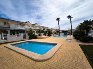 two swimming pools in a courtyard with palm trees at Bungalow Malibu Complex Doa Pepa- Rojales in Ciudad Quesada