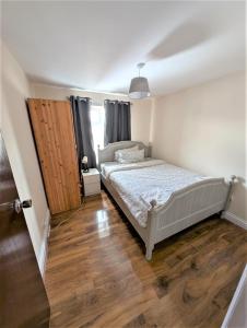 Un dormitorio con una cama y suelo de madera. en Spacious 5 bedroom House - 10min walk to Becrontree Station, en Dagenham