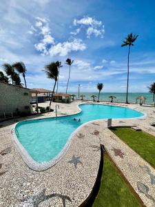 einen Pool am Strand mit Palmen in der Unterkunft Flats Privé Village Galés in Maragogi