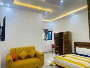 Résidences hôtels sibontour في ياموسوكرو: غرفة نوم بسرير واريكة صفراء