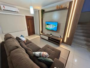 a living room with a couch and a flat screen tv at Sobrado, 4 Quartos, Piscina, até 12 pessoas in Foz do Iguaçu