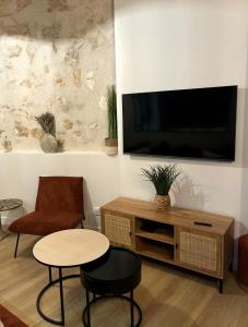 een woonkamer met een televisie en een tafel en stoelen bij La Suite des Arènes in Bourges