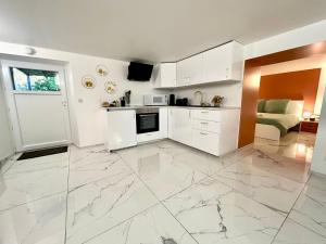 a kitchen with white cabinets and a large marble floor at Ti Dous - Terrasse, Jardin, Proche Centre ville in Le Faouët