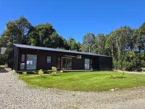 a black house with a lawn in front of it at suite campestre con terraza in Puerto Varas