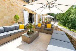 a patio with a couch and an umbrella at Château La Carrière in Saint-Cyprien