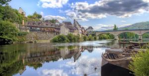 une rivière dans une ville avec un pont et des bâtiments dans l'établissement Charmant Duplex en bord de Dordogne - Argentat- Corrèze, à Argentat