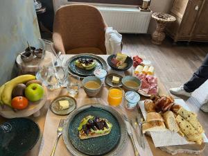 a table topped with plates of breakfast foods and fruit at La Ferme de la Cour in Herbeumont