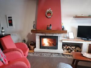 a living room with a fireplace and red chairs at El Cerrillo II in San Martín del Pimpollar