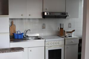 a kitchen with white cabinets and a sink at Casa delle Rose Terrazza vista mare panoramica e relax a Cala Gonnone, WiFi, AC in Cala Gonone