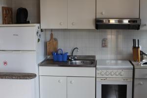 a white kitchen with a sink and a stove at Casa delle Rose Terrazza vista mare panoramica e relax a Cala Gonnone, WiFi, AC in Cala Gonone