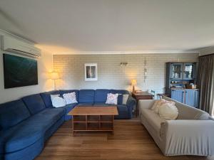a living room with a blue couch and a table at Parkview 1- Black Head NSW in Hallidays Point