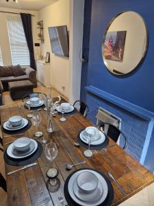 a wooden table with plates and glasses and a mirror at 4br House Popular Ravenhill Road in Belfast