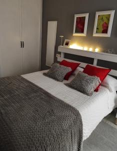 Un dormitorio con una cama grande con almohadas rojas. en Huétor Vega precioso apartamento, en Huétor Vega