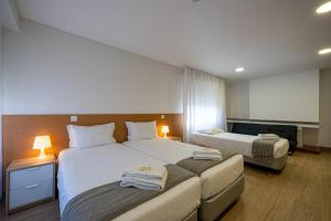 a hotel room with two beds and two lamps at Central Suites 3 in São João da Madeira