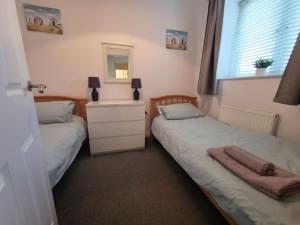 two beds in a bedroom with a mirror and a dresser at 2 Belmont Court in Woolacombe