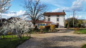 Una gran casa blanca con un patio con árboles en flor. en Gites de la Vergne, en Adriers