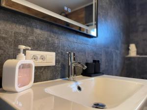 a bathroom sink with a soap dispenser on it at V apartament - ultra central Otopeni in Otopeni +62 photos