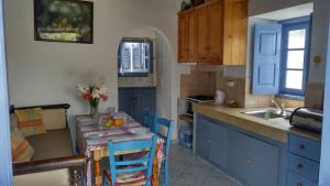 een keuken met blauwe kasten en een tafel met fruit erop bij Aloe House in Patmos