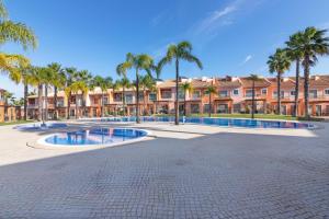 einen großen Innenhof mit Palmen und Häusern in der Unterkunft Jardins Vale de Santa Maria G, with pool in Albufeira