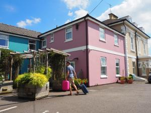 a man walking in front of a pink house at Cotswold Aparthotel in Stroud