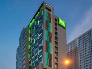 贝克西ibis Styles Bekasi Jatibening的上面有绿色标志的高楼