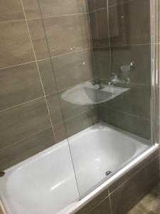 a bath tub with a shower and a sink at Apart Duclout Monte Grande a 15 minutos del Aeropuerto Ezeiza in Monte Grande