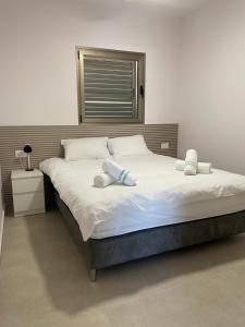 Una cama grande con sábanas blancas y almohadas. en Amdar 2BR Garden Apt EILAT, en Eilat