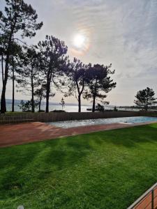 a lawn with trees and the ocean in the background at Desconectaengalicia Rincón de Cabodeiro in Isla de Arosa