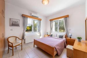 a bedroom with a bed and a desk and two windows at The Arches Villa in Lachi +28 photos