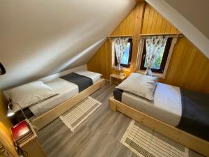 a attic bedroom with two beds and two windows at Princess Mojca Holiday House in Bled