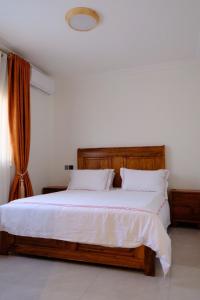 a bedroom with a large wooden bed with white sheets at Flic and Flac Apartments Apt 6 in Kampala