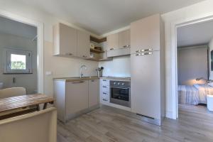 a kitchen with white cabinets and a table and a bed at Il Quartiere apt Pianosa in Pomonte +11 photos
