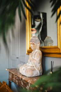 une statue assise sur une table devant un miroir dans l'établissement La Môme — Parking, quartier historique & animé, à Caen