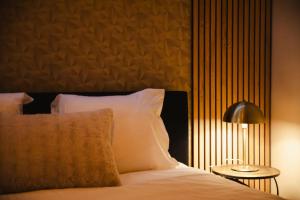 une chambre avec un lit avec des oreillers blancs et une lampe dans l'établissement La Môme — Parking, quartier historique & animé, à Caen