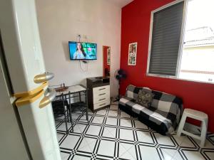 a living room with a couch and a tv at Kitnet funcional perto da praia Ocian! in Samaritá