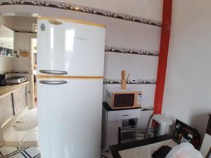 a kitchen with a refrigerator and a microwave at Kitnet funcional perto da praia Ocian! in Samaritá