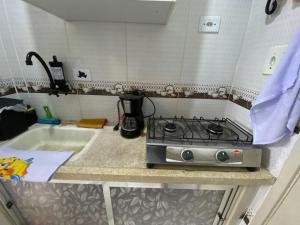 a kitchen counter with a stove and a sink at Kitnet funcional perto da praia Ocian! in Samaritá